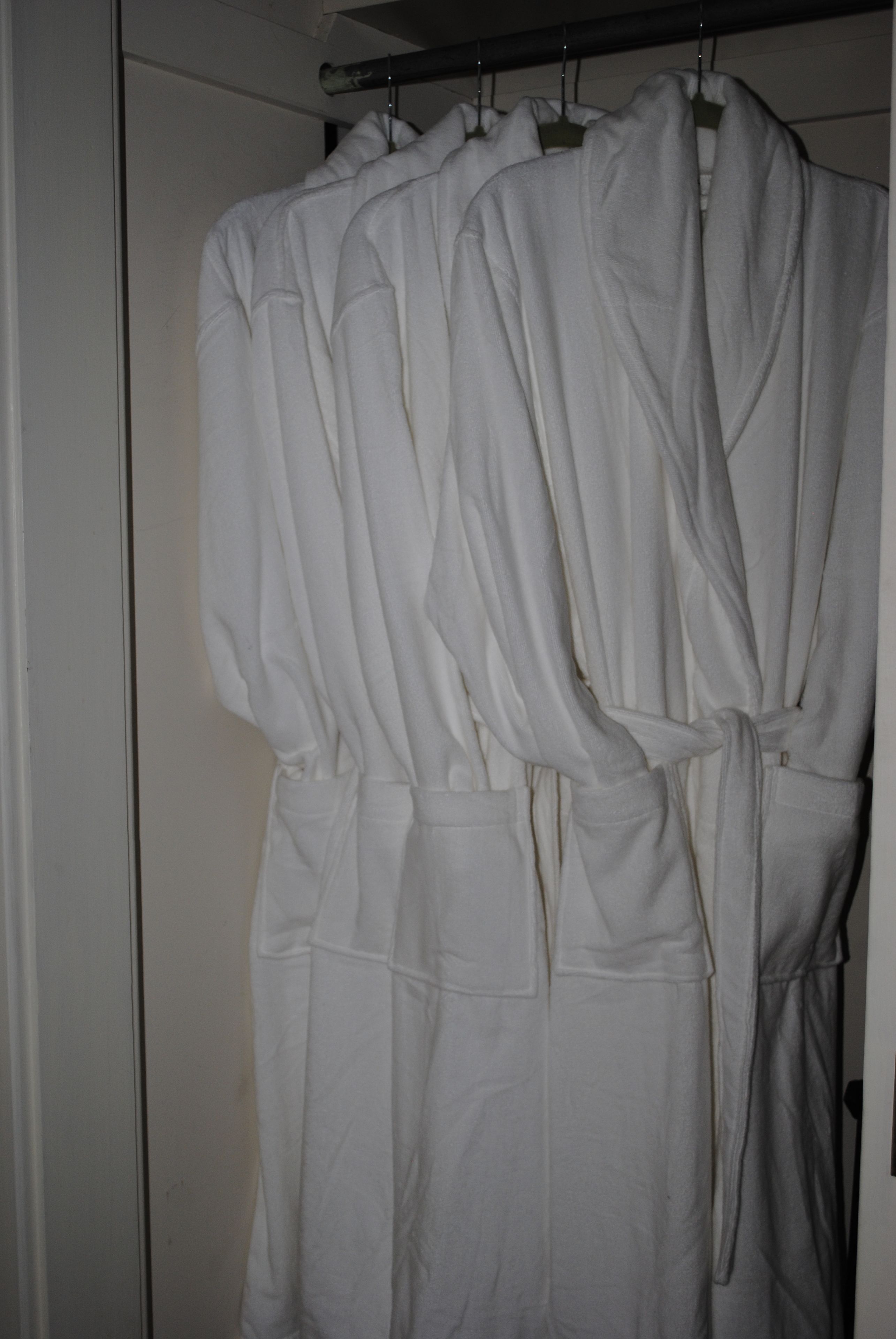 A white robe hanging on a rack in a bathroom.