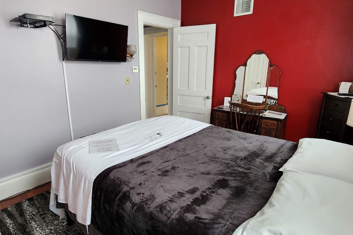 A hotel room with a bed, a television mounted on the wall, a dresser, and a mirror.