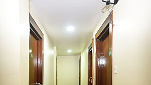 A hallway with patterned carpet, wooden doors, and a ceiling-mounted light fixture. - Karma Hotel Nepal (Kathmandu)