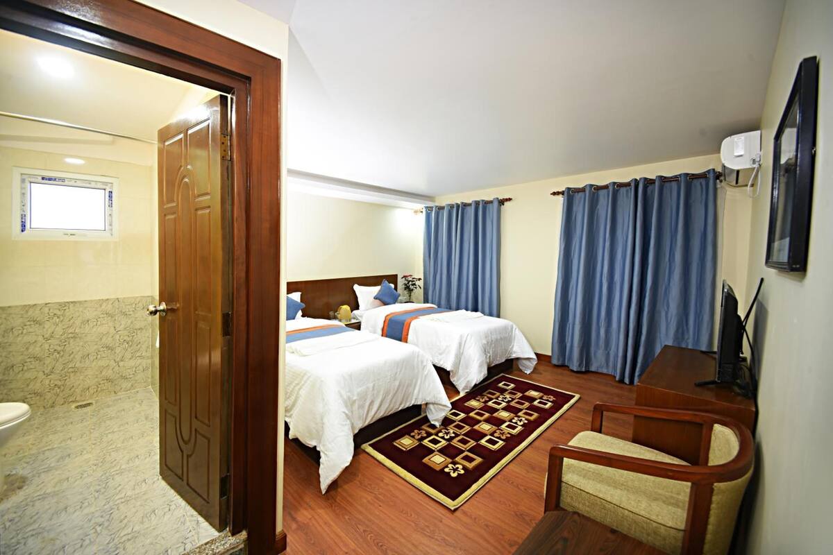 A hotel room with two beds, a bathroom, a desk, and a chair.