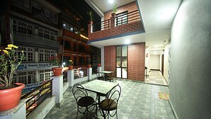 A courtyard with a table and chairs, surrounded by buildings with balconies and potted plants. - Karma Hotel Nepal (Kathmandu)