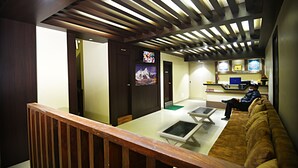 A hotel lobby with a wooden ceiling, a reception desk, a couch, and a television screen. - Karma Hotel Nepal (Kathmandu)