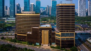 A modern high-rise building with a prominent entrance and a large glass facade.