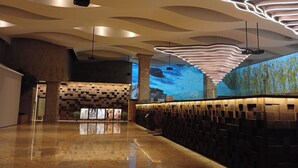 A modern interior with a reflective floor, a large digital mural, and a unique ceiling design.
