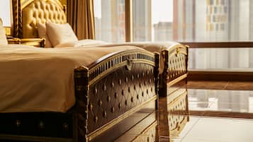 Un dormitorio lujoso con una cama grande, un cabecero dorado y vistas a la ciudad a través de amplios ventanales.