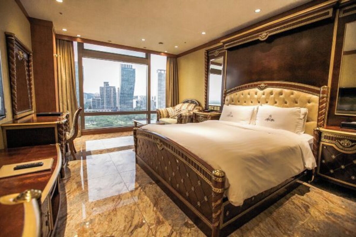 A spacious hotel room with a large bed, a desk, and a view of the cityscape.