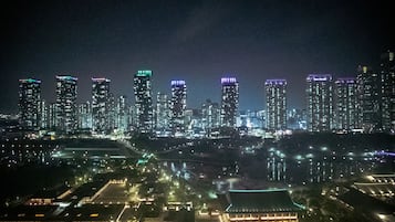 A nighttime cityscape with illuminated skyscrapers and a traditional building in the foreground.