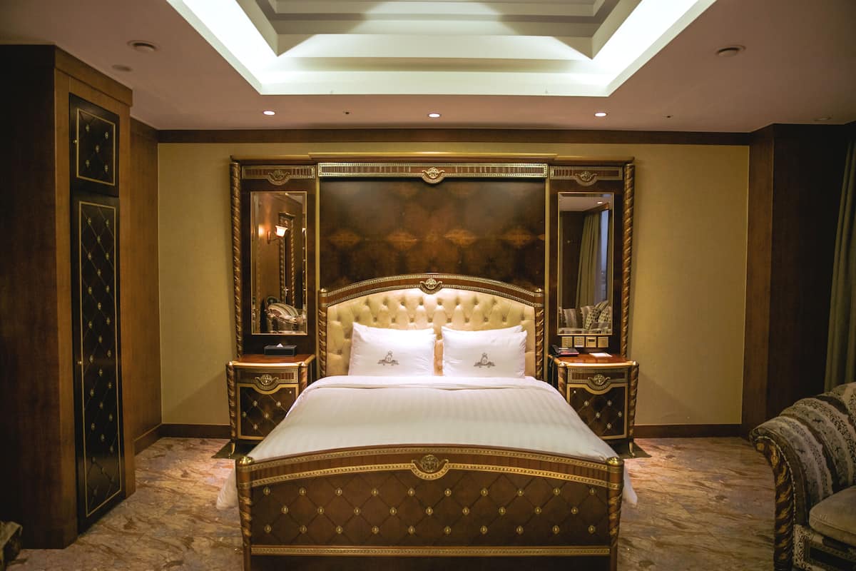 Un dormitorio lujoso con una cama grande, un cabecero decorativo y mesitas de noche a juego.