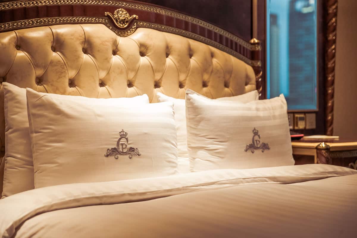 Una cama lujosa con cabecera capitonada y almohadas decorativas.