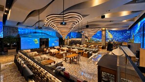 A modern interior with a bar area, seating arrangements, and a large screen displaying an underwater scene. - The Central Park Hotel Songdo (Incheon)
