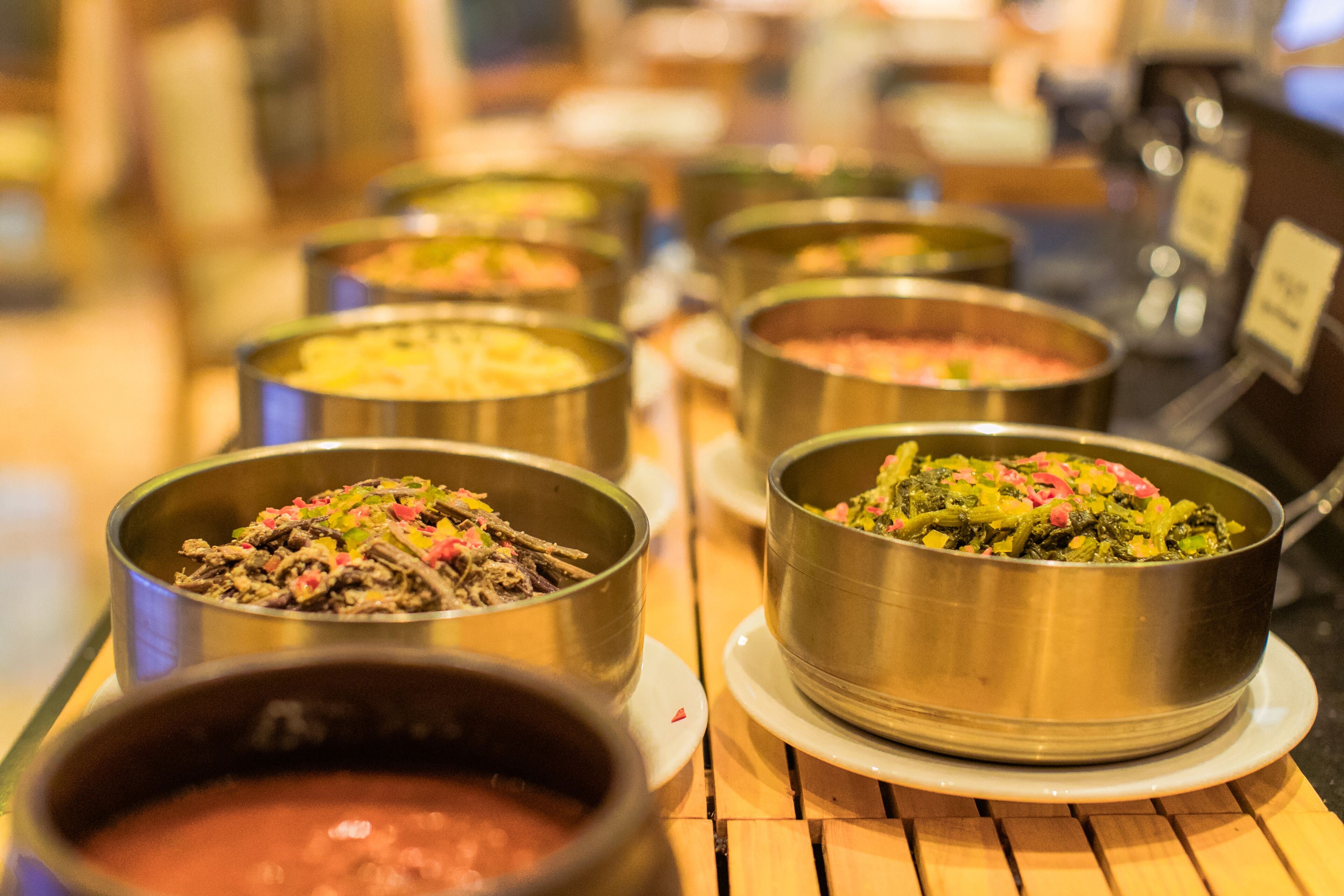 A buffet table with various dishes in metal bowls.