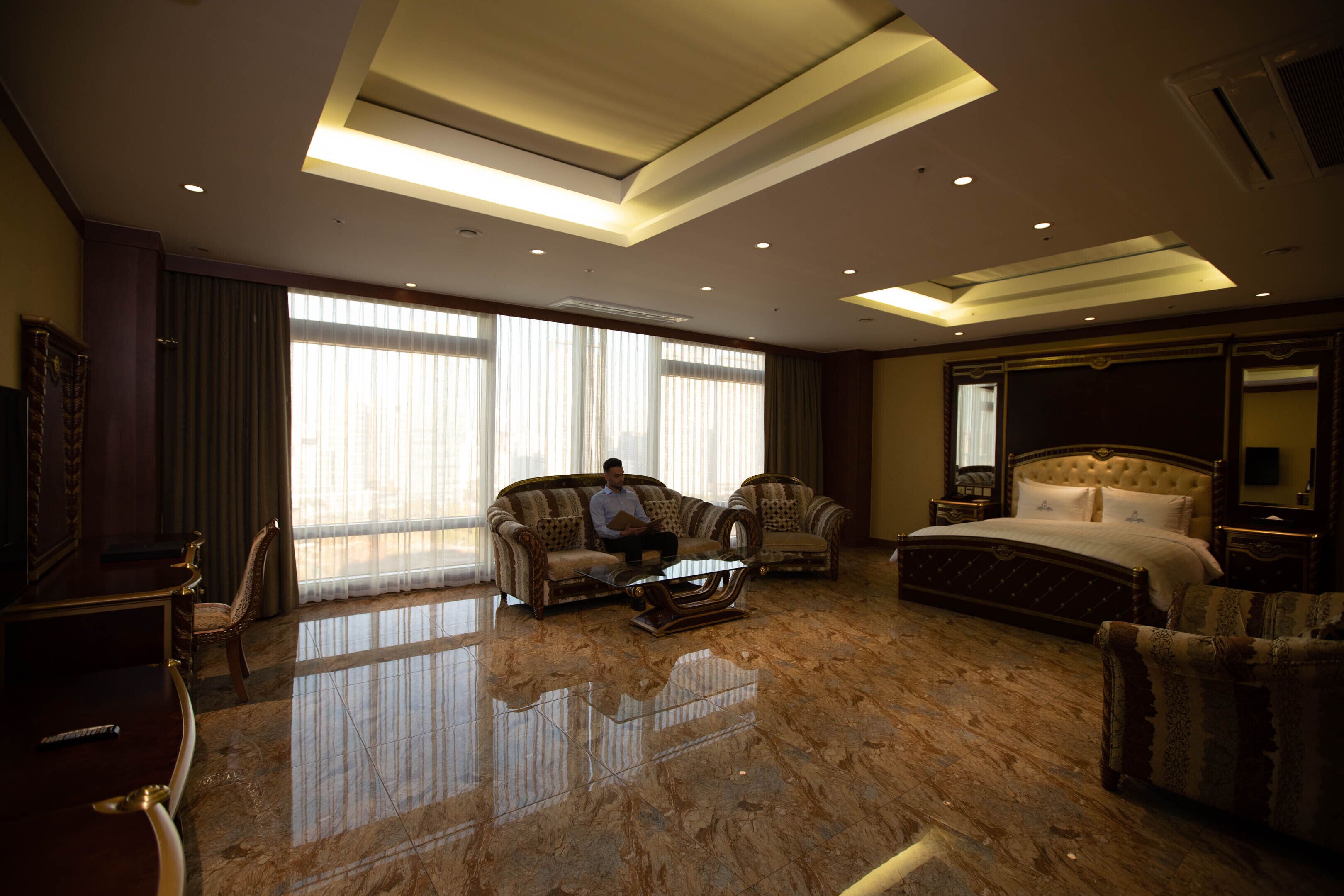 Une chambre d’hôtel spacieuse avec un grand lit, un coin salon comprenant deux canapés, une table basse et un téléviseur.