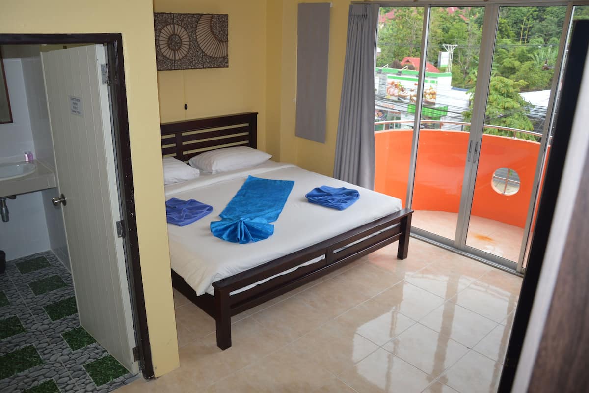 A hotel room with a bed, a bathroom, and a balcony with a view of the city.