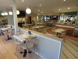 Un restaurante con mesas y sillas de madera, una barra con un menú y una pantalla de televisión al fondo.