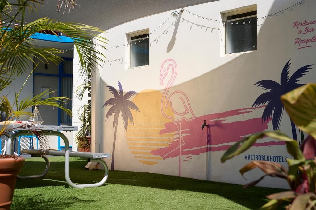 A wall with a mural of palm trees and a flamingo, a pool table, and a sign for a restaurant and bar.