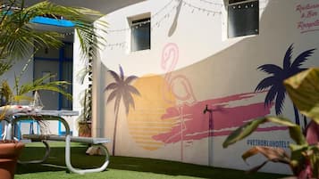 Una pared con un mural de palmeras y un flamenco, una mesa de billar y un letrero para un restaurante y bar.