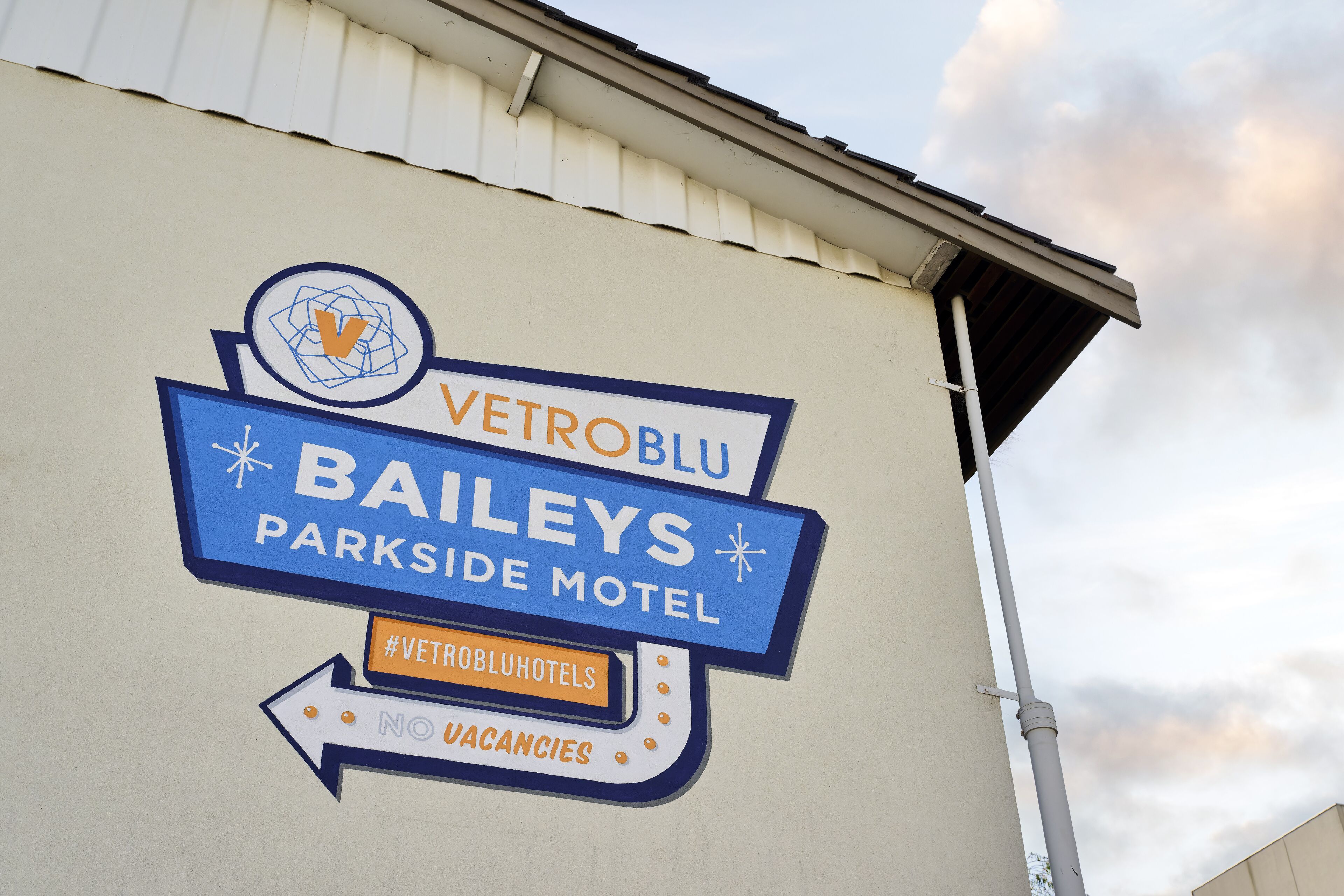A motel sign with the name "VetroBlu Baileys Parkside Motel" and a hashtag "#VetroBluHotels".