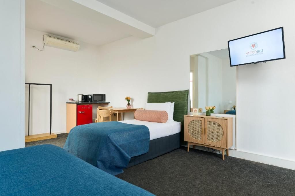 Una habitación de hotel con una cama, un escritorio, un televisor y un armario.