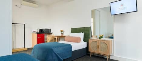 Una habitación de hotel con una cama, un escritorio, un televisor y un armario.