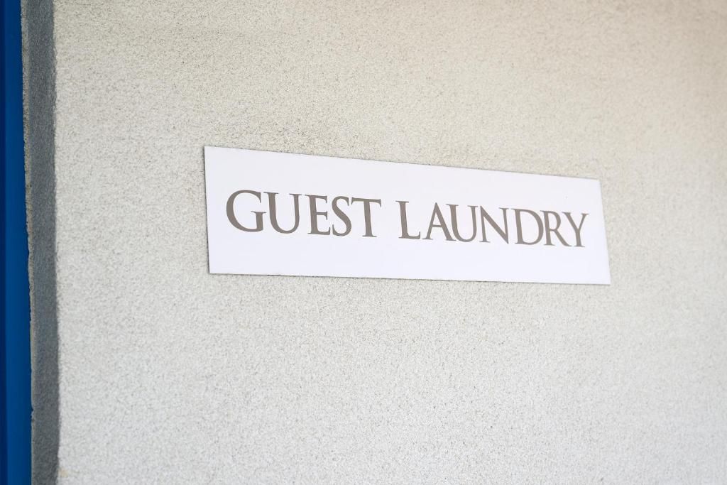 Een bord met de tekst 'GUEST LAUNDRY' op een muur.