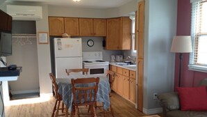 A compact kitchen with wooden cabinets, a dining table with chairs, a refrigerator, a stove, and a sink. - Briarwood Coastal Cottages & Lodge (Union)