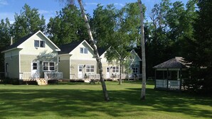 A row of two-story houses with a front porch and a gazebo in a grassy yard. - Briarwood Coastal Cottages & Lodge (Union)