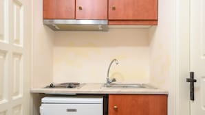 A compact kitchen with wooden cabinets, a white refrigerator, and a stainless steel sink. - Kahlua Studios (Naxos)