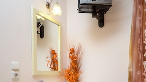 A bathroom with a vanity, a mirror, a television mounted on the wall, and a shower curtain. - Kahlua Studios (Naxos)
