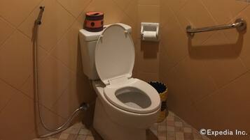 Un baño con inodoro, ducha y barra de apoyo.