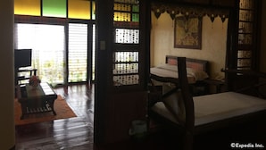 A traditional Japanese-style room with tatami flooring, a low bed, and a television on a stand. - Bohol Bee Farm (Dauis)