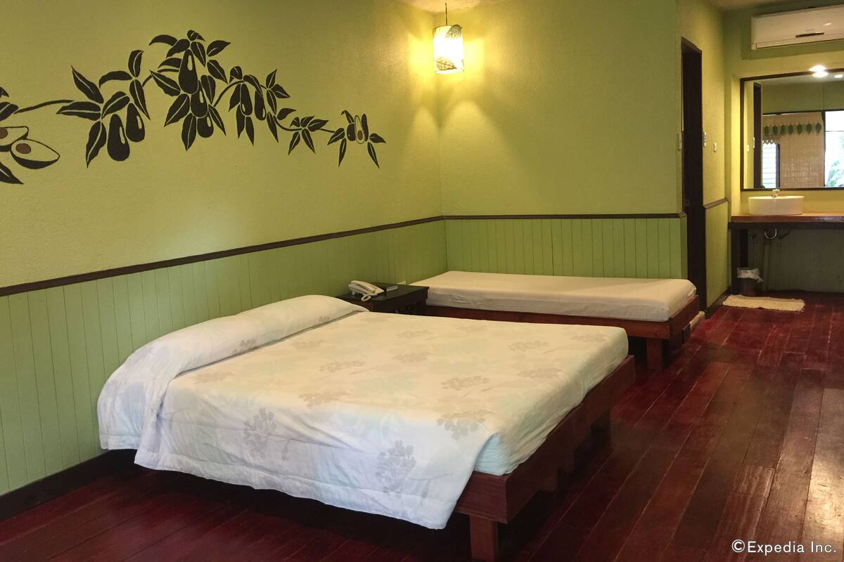 A room with two single beds, a wall-mounted phone, a light fixture, and a mirror above the sink.