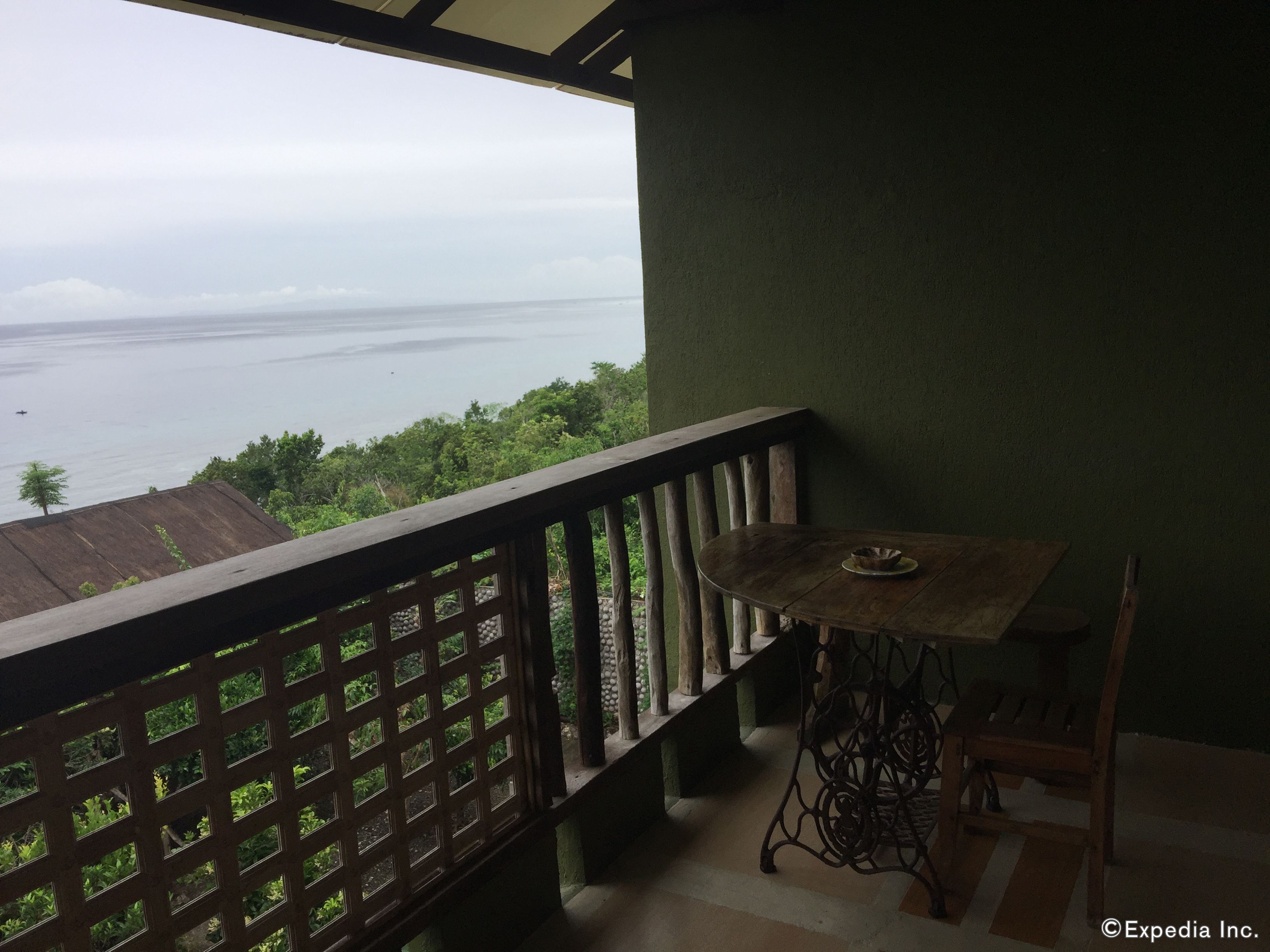 A balcony with a view of the sea, a wooden table, and a chair.