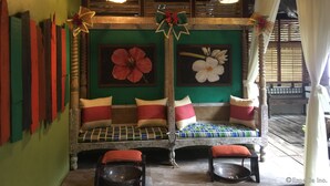 A traditional wooden bench with cushions, a woven basket, and a bowl on the floor. - Bohol Bee Farm (Dauis)
