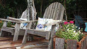 Una terraza rústica de madera con una silla de madera y una jardinera con flores.
