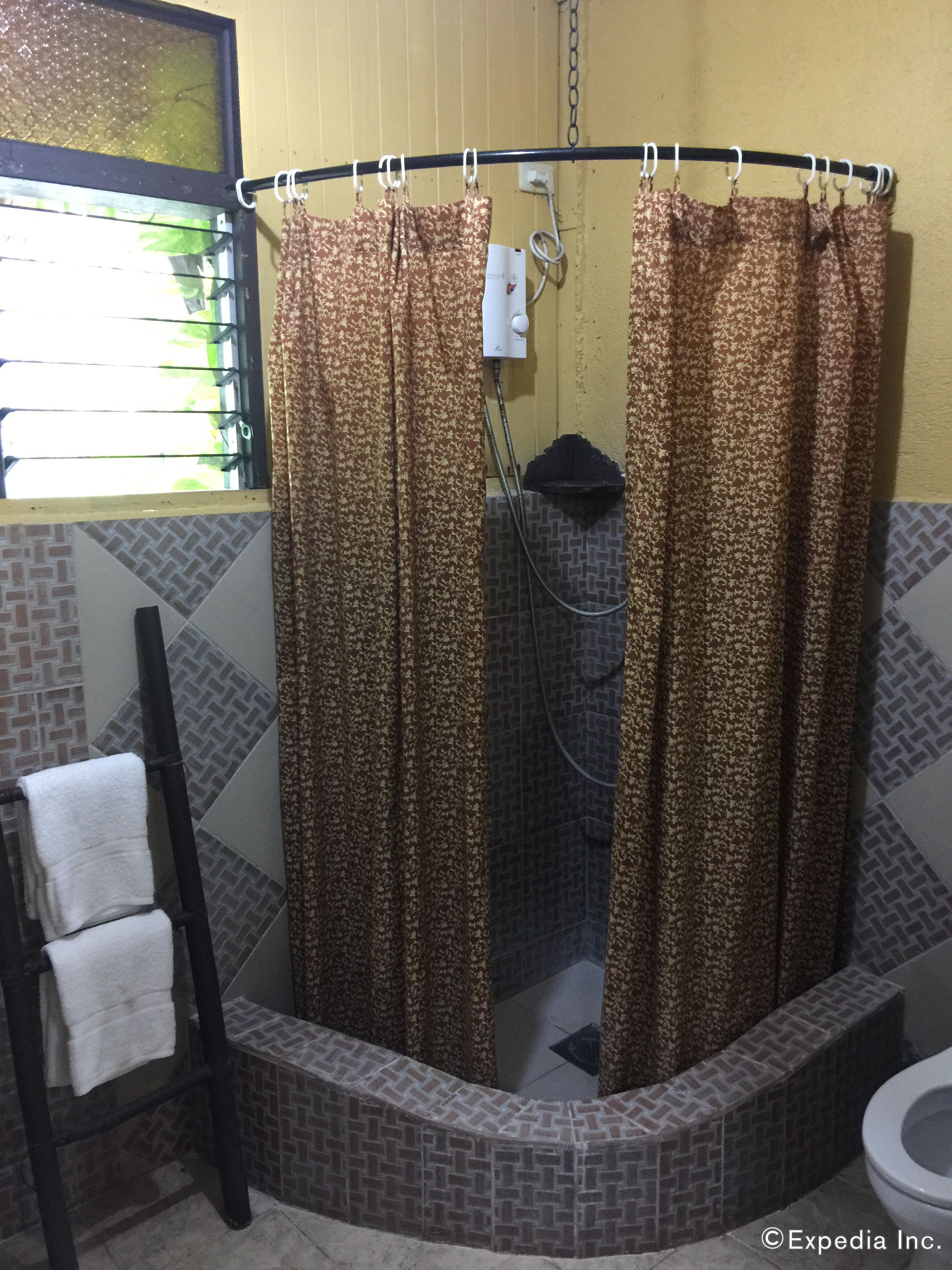 A bathroom with a shower, a towel rack, and a toilet.
