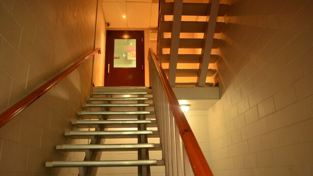 A staircase with metal handrails and a wooden railing, leading to a door with an 'EXIT' sign. - Bexon Rooms - Hotel Downtown Windsor (Windsor)