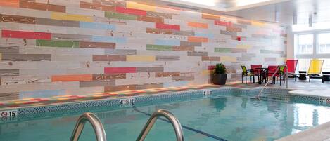 Ein Innenpool mit farbenfroher Mosaikwand und Liegebereich am Beckenrand.