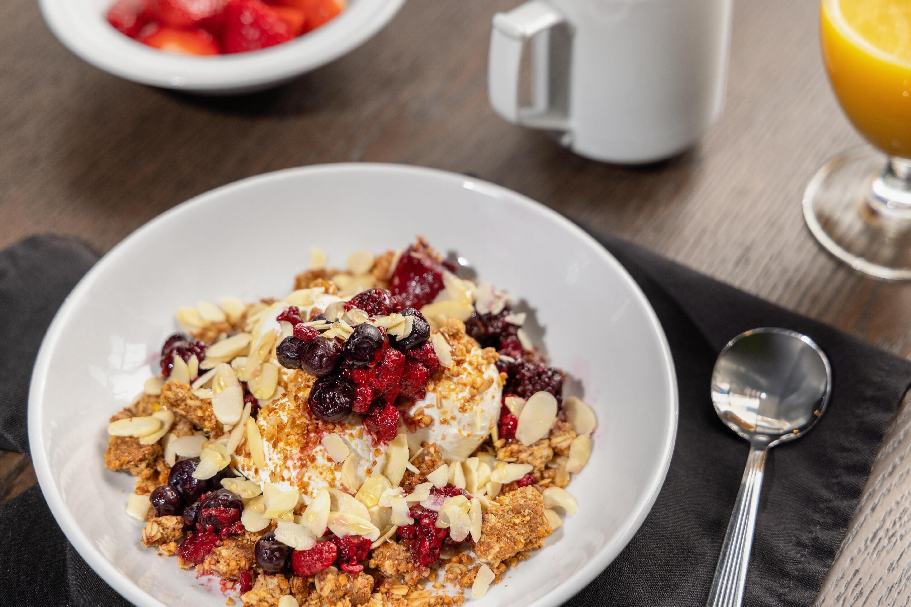 A bowl of cereal with berries and almonds on a dark napkin.