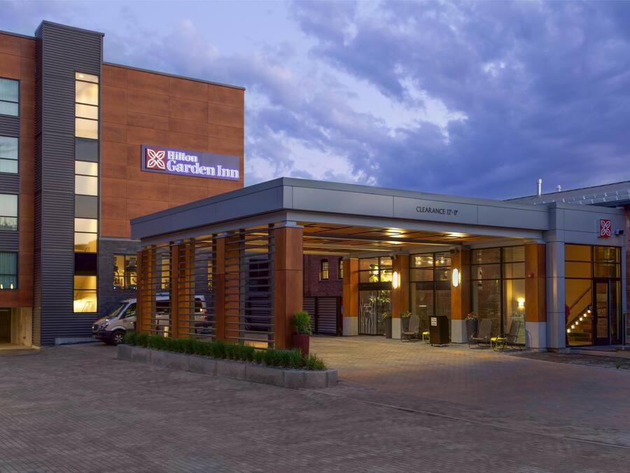 A Hilton Garden Inn with a modern exterior, a covered entrance area, and a brick building.