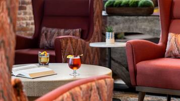 Un rincón acogedor con una mesa redonda, un libro y dos bebidas.