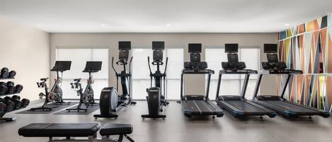 A gym with treadmills, elliptical machines, and free weights.