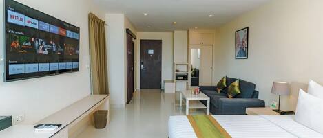 Habitación de hotel con cama, escritorio, televisor en la pared, sofá y una mesita.