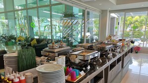 A buffet setup with various food stations, plates, and condiments. - Tamarind Garden Hotel (Rayong)