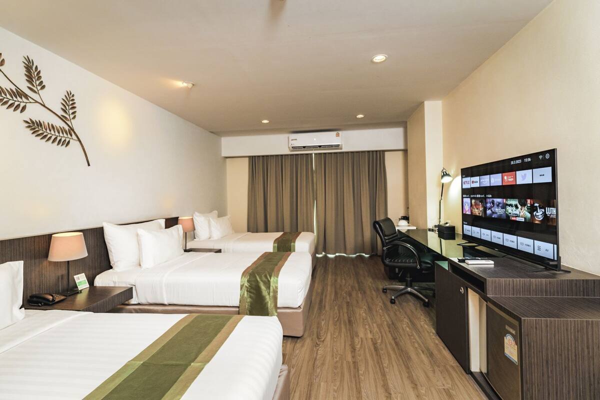 Ett hotellrum med två sängar, ett skrivbord, en TV och en luftkonditioneringsanläggning.