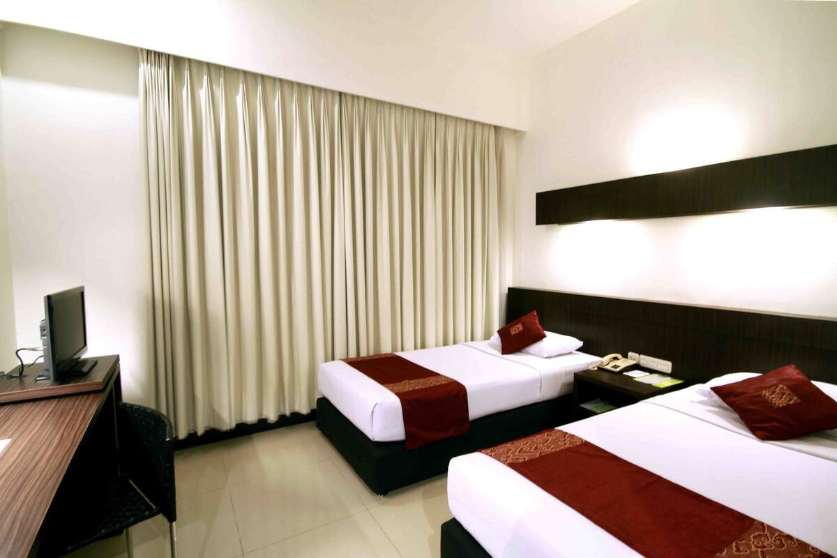 A hotel room with two beds, a desk with a computer, and a TV.