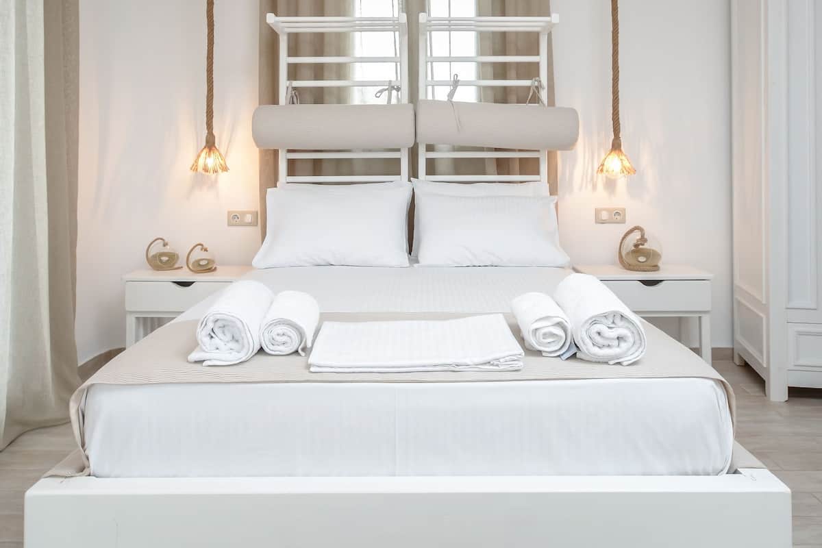 A modern bedroom with a white bed, bedside tables, and a ceiling light fixture.