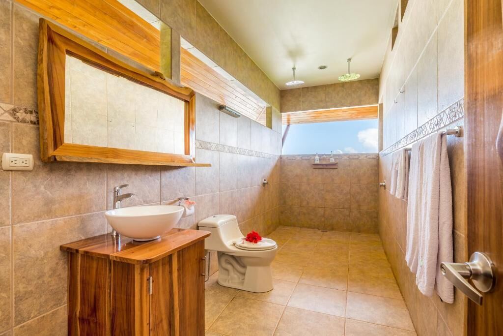 A bathroom with a wooden vanity, a white sink, a toilet, and a shower area.