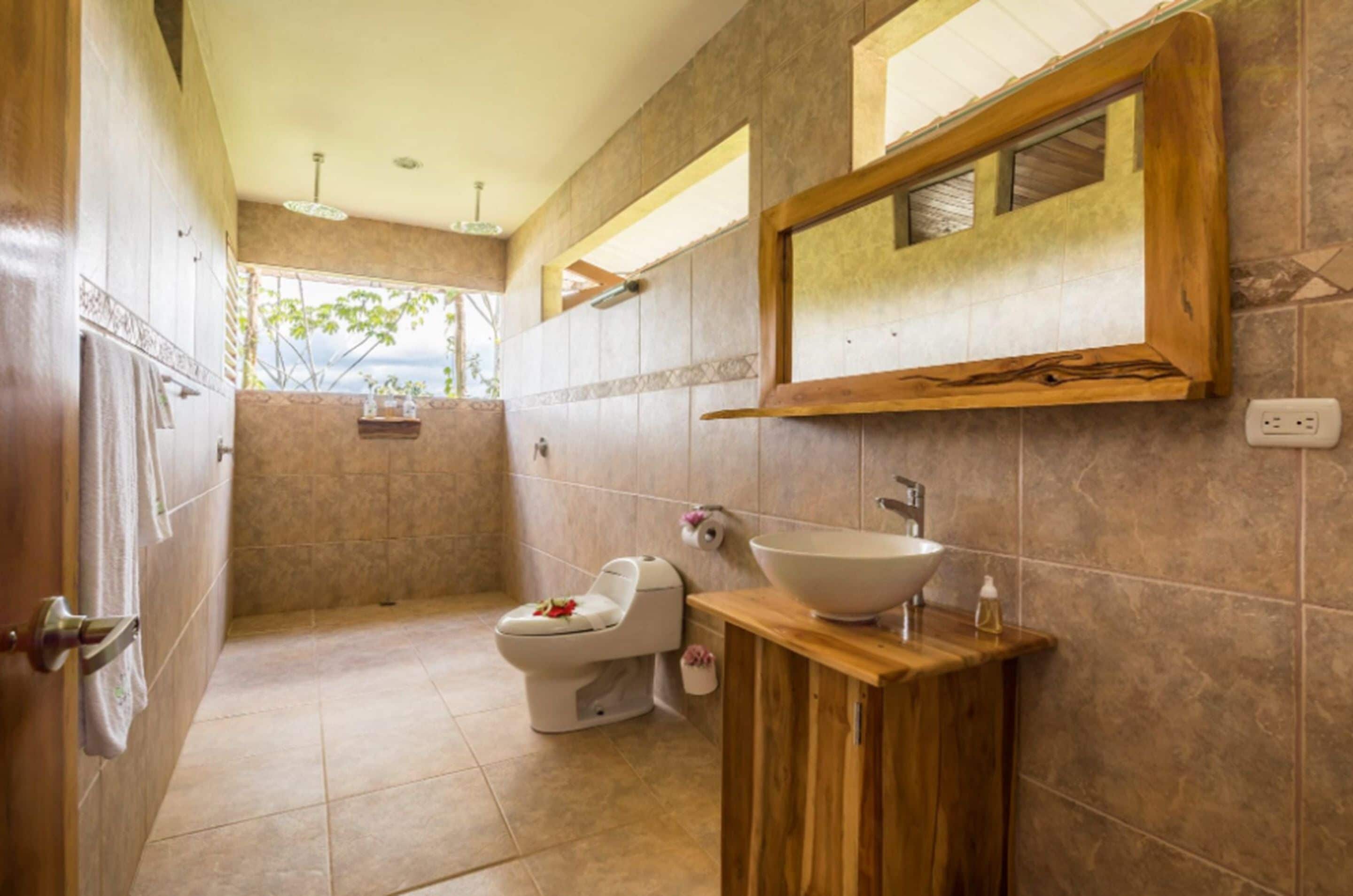 A modern bathroom with a large sink, a toilet, and a shower area.
