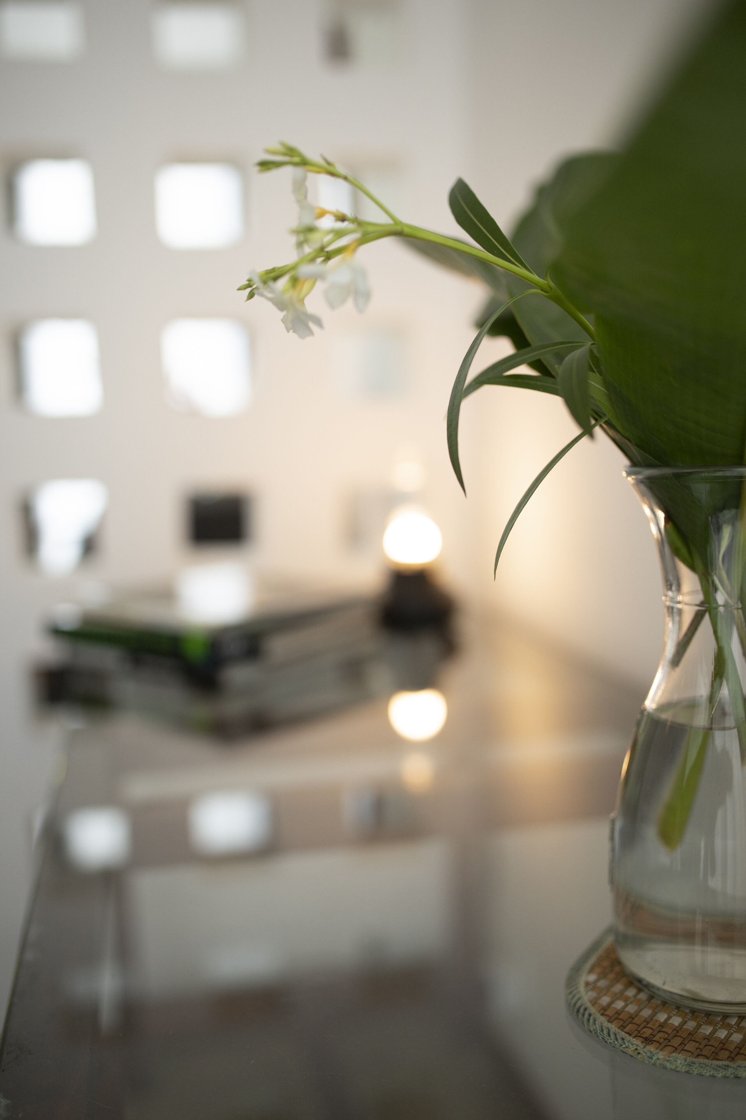 A clear glass vase with a single white flower on a table.