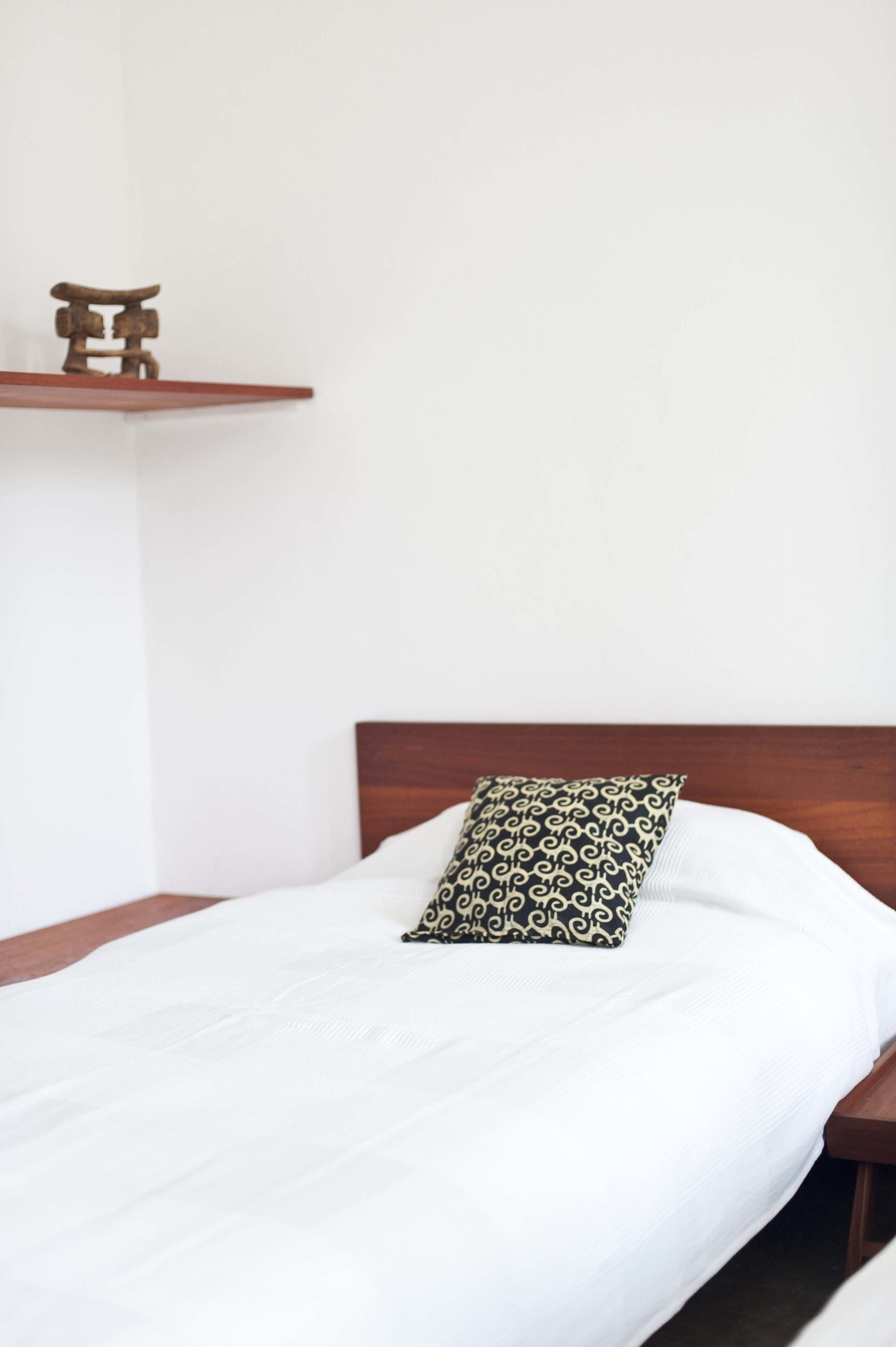 A single bed with a patterned pillow and a wooden headboard.